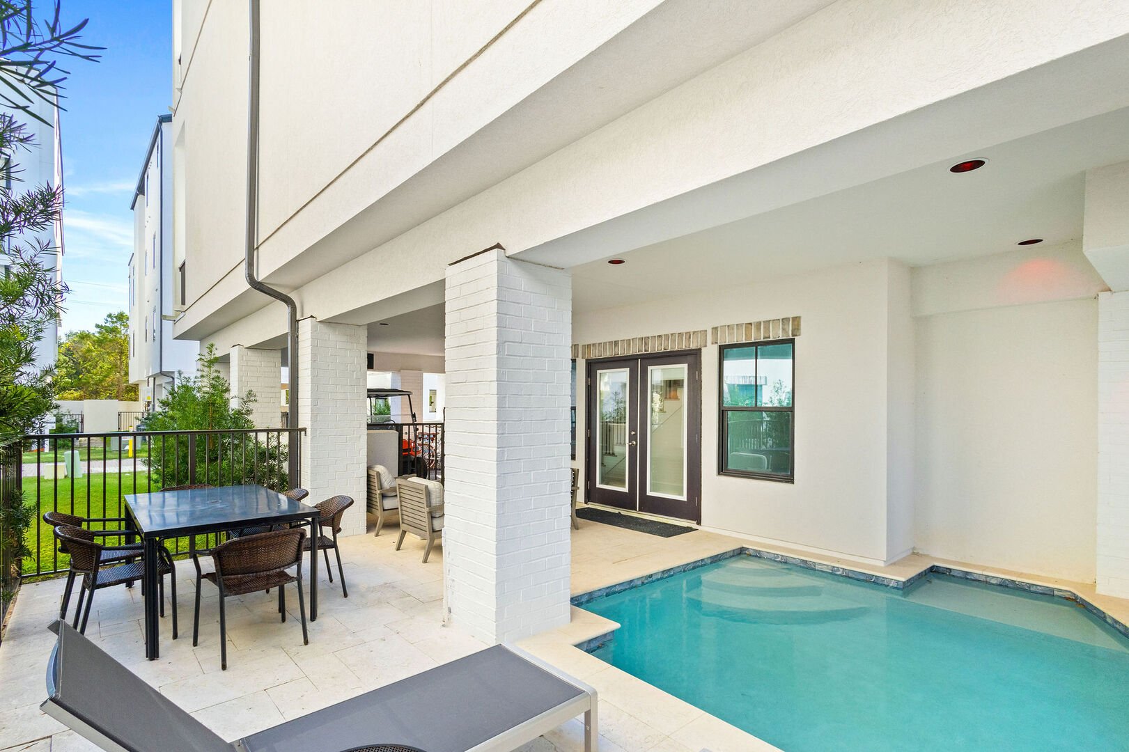 The back patio includes sun loungers, dining space and additional seating.