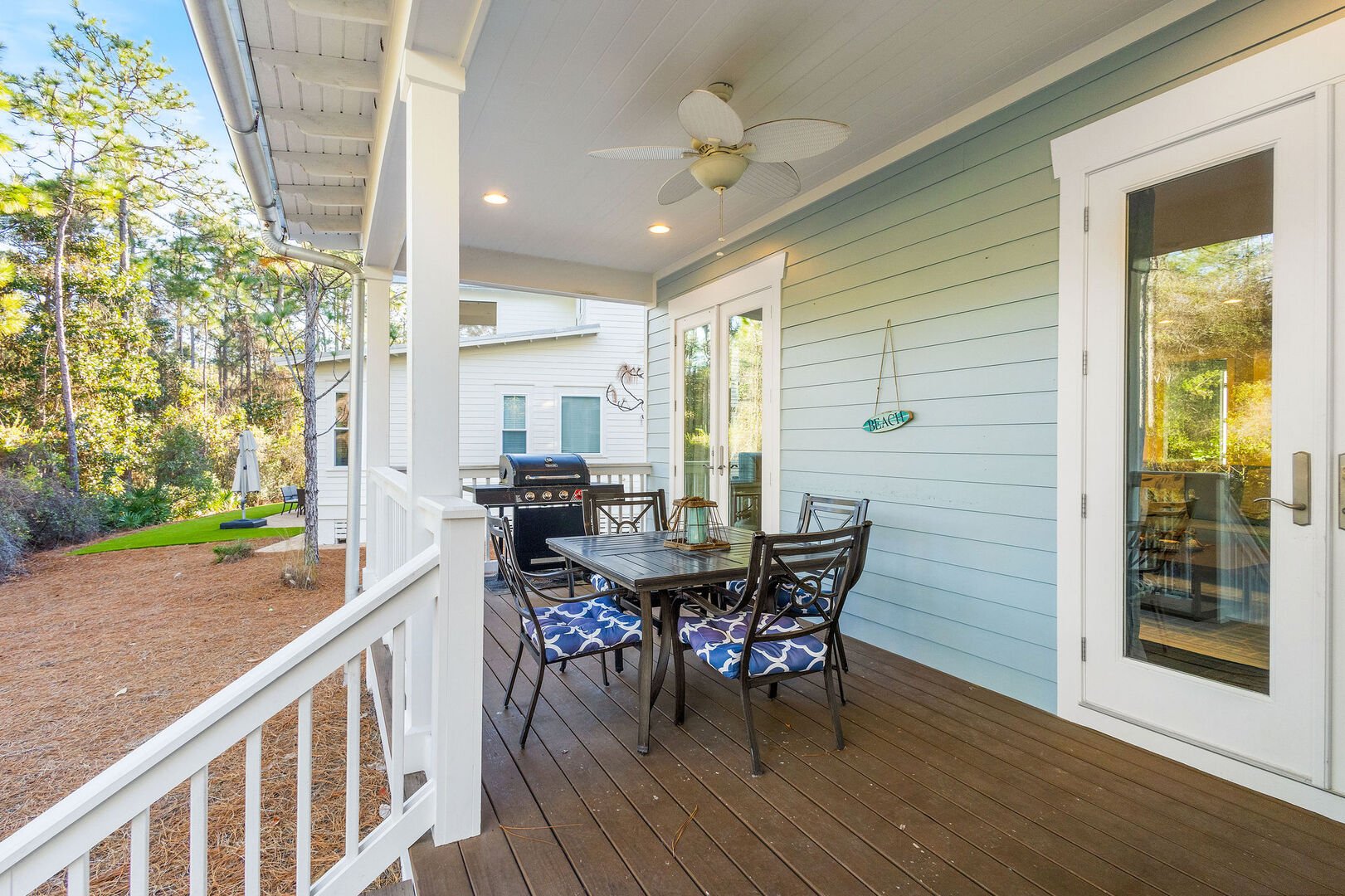 Covered porch off living room features seating and a gas grill.
