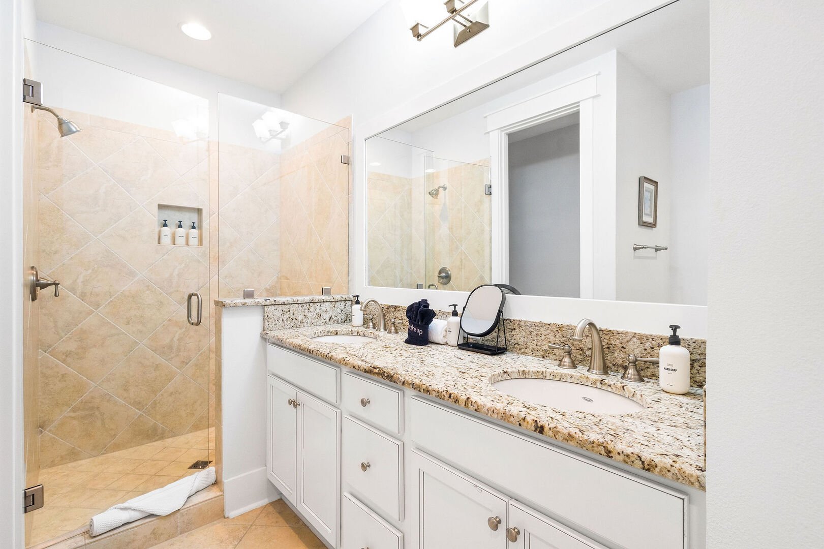 Bathroom features dual vanities and a walk-in shower.