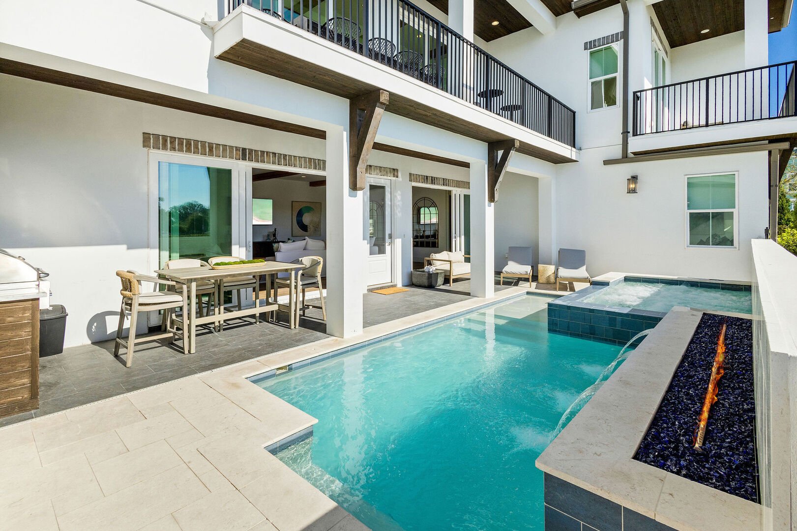 Upon entering the gate of the home, you are immediately greeted by the private pool which features a sitting spa and fire pit. Outdoor patio features sun loungers, seating and dining space.