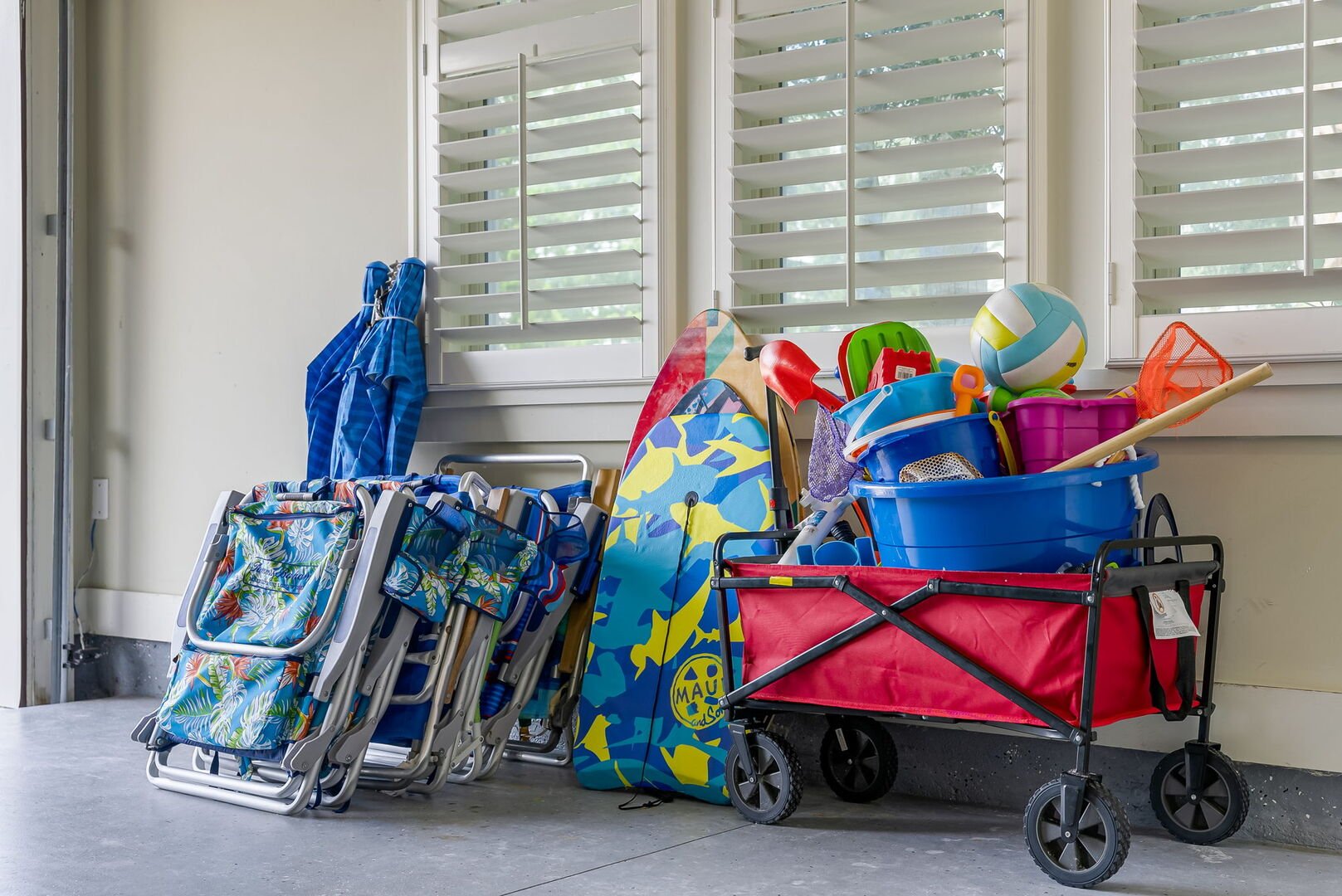Garage is packed with essentials for the beach with beach chairs, coolers, beach toys, wagon, umbrellas