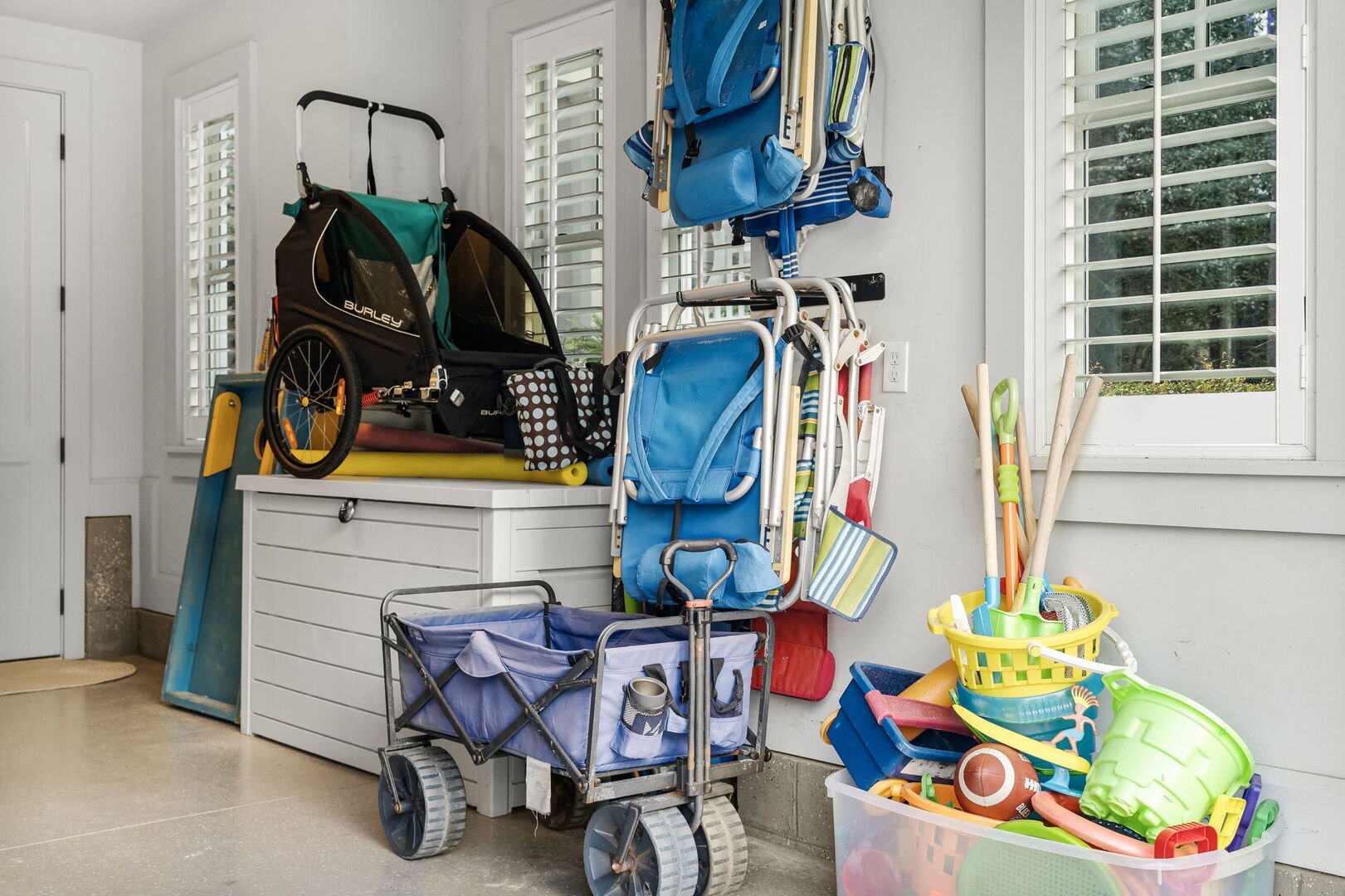 Garage is packed with essentials for the beach with beach chairs, coolers, beach toys, wagon, umbrellas